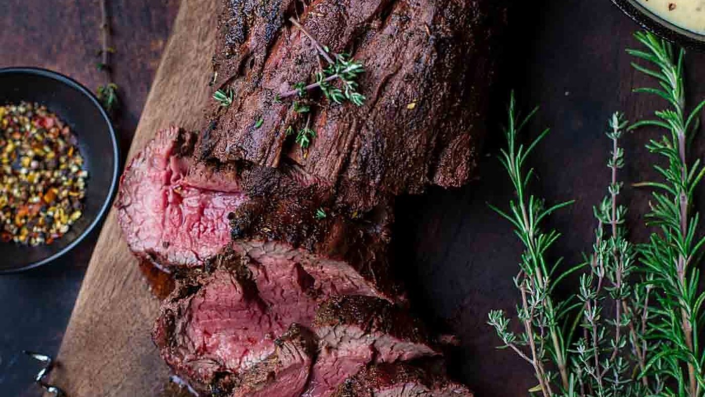 Sliced steak resting on a board with rosemary